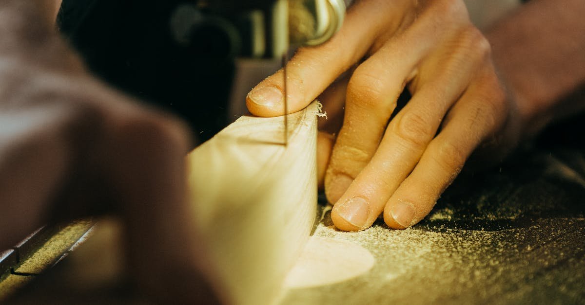 Close-up of a craftsman using a band saw to shape wood in a workshop setting.